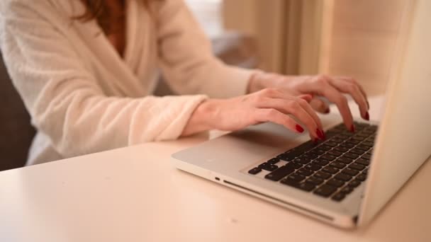 Teknologi koncept tæt op unge kvinde hænder arbejder online med bærbar computer i hvid badekåbe tidligt om morgenen derhjemme. Fjernarbejde, fjernundervisning – Stock-video