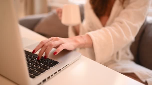 Teknologi koncept - närbild unga kvinna händer som arbetar online med bärbar dator i vit badrock tidigt på morgonen hemma. Fjärrarbete, distansutbildning — Stockvideo