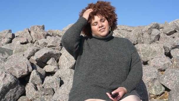 Bella felice sorridente plus size africana donna nera afro capelli in maglione grigio all'aperto godendo di tempo luminoso soleggiato e cielo blu. Corpo imperfezione, accettazione corpo concetto di diversità positiva — Video Stock