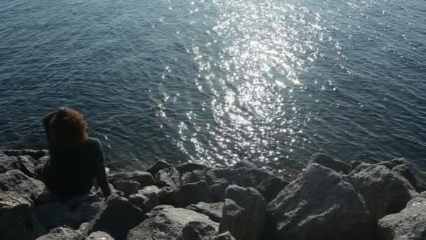 Vista posteriore plus size donna nera africana afro capelli all'aperto godendo tranquilla vacanza al mare serale al tramonto, tempo soleggiato, rocce, acqua blu dell'oceano. Concetto di diversità positiva del corpo — Video Stock
