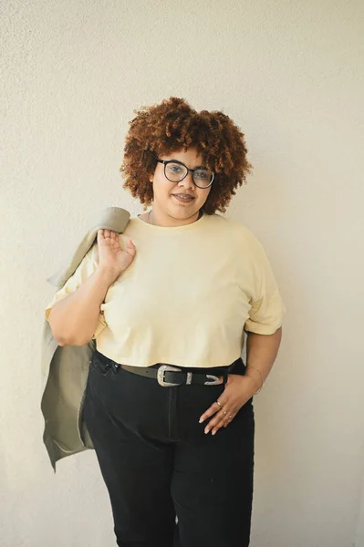 Bonita feliz sorrindo curvy plus size Africano preto mulher afro cabelo posando bege t-shirt, jeans, óculos elegantes no fundo bege. Imperfeição corporal, aceitação corpo conceito diversidade positiva — Fotografia de Stock