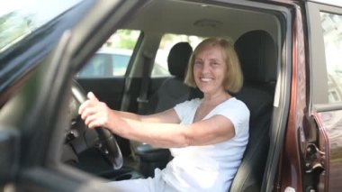 Yeni kahverengi arabasında oturan mutlu bir son sınıf öğrencisi, kameraya bakıp eğleniyor. Sürüş kursları ve hayat sigortası konsepti. Emekli insanlar aktivite kavramı.