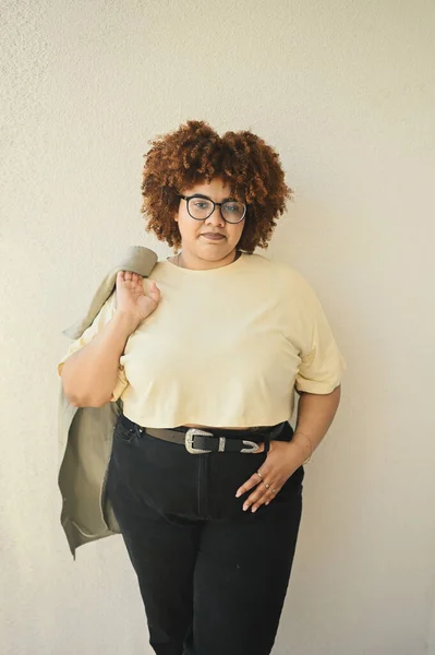 Bonita feliz sorrindo curvy plus size Africano preto mulher afro cabelo posando bege t-shirt, jeans, óculos elegantes no fundo bege. Imperfeição corporal, aceitação corpo conceito diversidade positiva — Fotografia de Stock