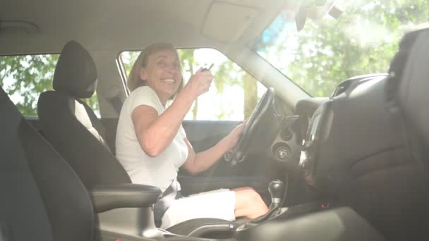 快乐的老年妇女坐在新车里，带着关键的微笑跳舞，看着镜头享受旅程。驾驶课程和人寿保险的理念。退休人员活动概念. — 图库视频影像