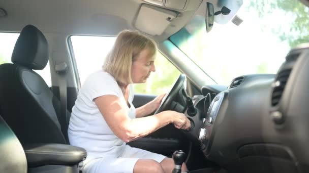 快乐的老年妇女驾驶新车，系好安全带，开动引擎，准备第一次旅行，享受旅程。驾驶课程和人寿保险概念。退休人员活动概念. — 图库视频影像
