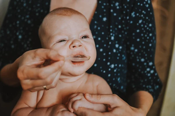 Mãe e recém-nascido engraçado choro emocional bebê menino nu toma medicação líquida ou xarope de remédio antipirético da colher. Criança saudável, conceito de hospital e maternidade feliz. Berçário. — Fotografia de Stock