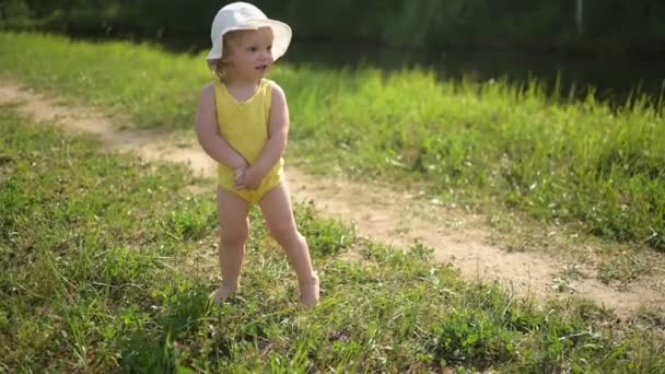 Little funny cute blonde girl child toddler in yellow bodysuit crying afraid of learning to swim outside at summer lake. Plus size body positive woman mother with baby swimming in natural pool. — Stock Video
