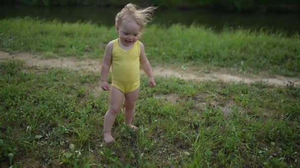 Little funny cute blonde girl child toddler in yellow bodysuit crying afraid of learning to swim outside at summer lake. Plus size body positive woman mother with baby swimming in natural pool. — Stock Video