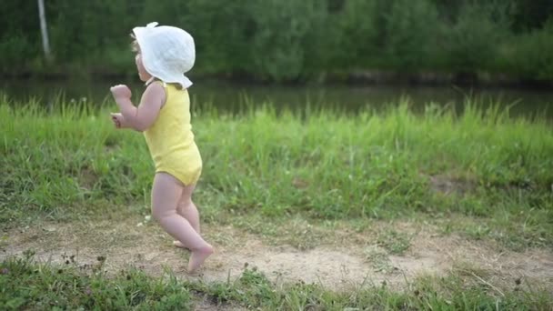 Malá zábavná blondýnka holčička batole ve žlutém obleku pláče strachem z toho, že se naučí plavat venku u jezera. Plus velikost těla pozitivní žena matka s dítětem plavání v přírodním bazénu. — Stock video