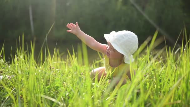 Το χέρι της μητέρας βοηθά να σταθεί Μικρή αστεία χαριτωμένο ξανθό κορίτσι παιδί νήπιο σε κίτρινο κοστούμι του σώματος και λευκό καπέλο κλαίει στον τομέα με πράσινο γρασίδι έξω το καλοκαίρι. Παιδικό ξέσπασμα. Υγιής έννοια παιδική ηλικία. — Αρχείο Βίντεο