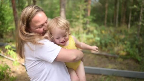 Petit bébé mignon tout-petit fille blonde avec des boucles sur les bras des mères. Mère et fille jouant passer du temps ensemble à l'extérieur à la campagne devant la cour été. Une famille heureuse saine concept d'enfance. — Video