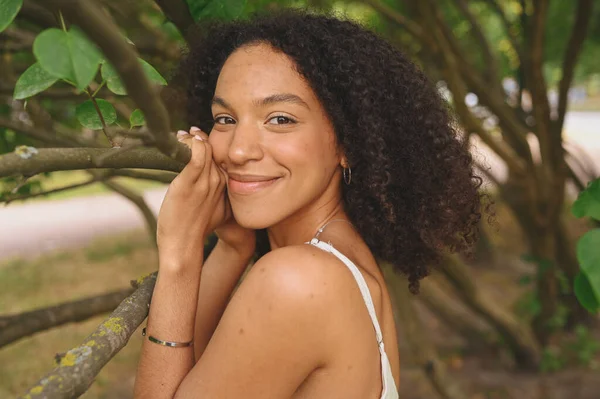 Fashion close-up portret van sensuele aantrekkelijke jonge natuurlijk mooie Afro-Amerikaanse vrouw met afro haar poseren in de natuur park in groen gebladerte. — Stockfoto