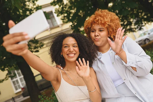 Indah bahagia lesbian Afrika Amerika pasangan Memeluk membuat selfie sekitar lanskap jalan kota di musim panas. Konsep komunitas LGBT. Teman-teman wanita tersenyum menikmati saat-saat cinta bersama — Stok Foto