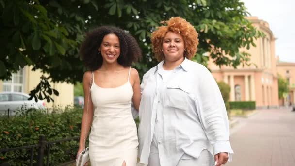 Bella bella felice lesbica coppia afro-americana a piedi abbracciando intorno paesaggio urbano di strada in estate. Il concetto di comunità LGBT. Amici femminili sorridenti godendo momenti d'amore insieme — Video Stock