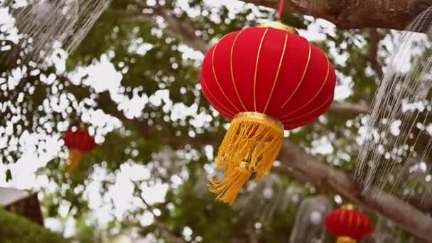 在中国的旅行中，中国的红灯笼挂在树上，迎风摇曳着绿叶和枝条，为中国农历新年大旗的背景划上了句号. — 图库视频影像