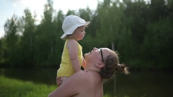 Petit bébé mignon tout-petit fille blonde boucles jaune combinaison chapeau blanc sur les bras des mères. Maman prend fille enfant jouant à l'extérieur à la campagne l'été. Une famille heureuse saine concept d'enfance — Video