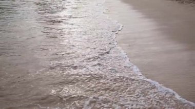 Kumlu sahile gelen bir deniz ya da okyanus dalgasının yüzeyi yakın çekim dokusu. Su ve köpükle dolu doğal bir arka plan. Yavaş çekim yaz tatili konsepti.