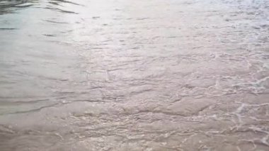 Kumlu sahile gelen bir deniz ya da okyanus dalgasının yüzeyi yakın çekim dokusu. Su ve köpükle dolu doğal bir arka plan. Yavaş çekim yaz tatili konsepti.