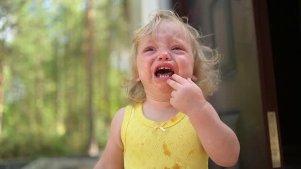 Närbild porträtt av små roliga söta blonda flicka barn småbarn i gul smutsig body suit gråter utanför på sommaren landsbygden. Barnsligt utbrott. Friska barndomskoncept. — Stockvideo
