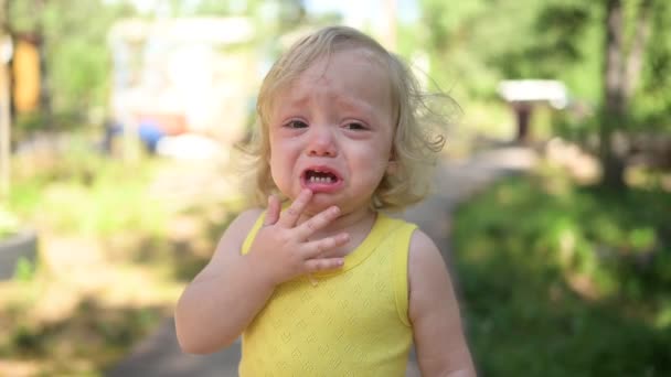 Närbild porträtt av små roliga söta blonda flicka barn småbarn i gul body suit gråter utanför på sommaren. Barnsligt utbrott. Friska barndomskoncept. — Stockvideo