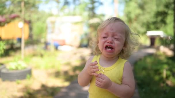 夏天，穿着黄色紧身衣的可爱的金发小女孩在外面哭泣。孩子气的脾气健康童年概念. — 图库视频影像