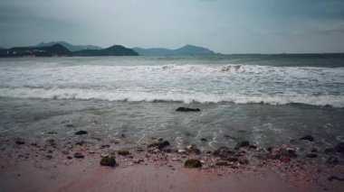 Sanya, Hainan 'da büyük ve modern bir sahil kasabası. Gökdelenleri var. Rüzgarlı ve fırtınalı havada, depresif su renklerinde dalgalar sörf yapar. Kasvetli deniz ya da okyanus .