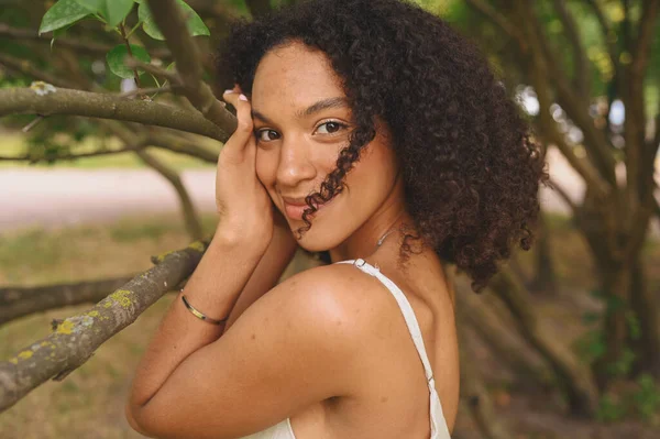 Fashion close up portrait of sensual attractive young naturally beautiful African American woman with afro hair posing in nature parkland in green foliage. — Stock Photo, Image