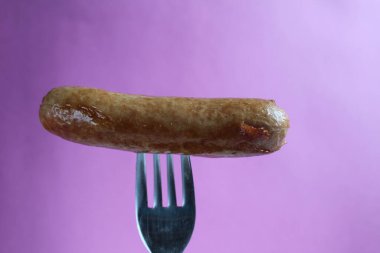 Sosis, kızarmış sosis, mor bir fuşya arka plan fotokopi alanının çatalına tutturulur.