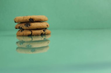 Çikolotalı kurabiyeler birbiri üzerine yığılmış. Fotokopi alanının kenarındaki yeşil buzlu arka planda.