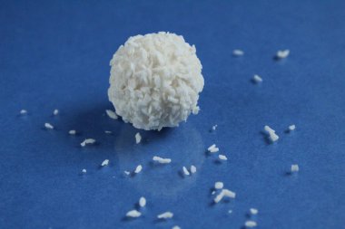 Fotokopi uzayının parlak mavi arka planına serpiştirilmiş hindistan cevizi parçacıklı beyaz bir şeker.