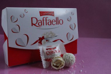 Beyaz şekerler yuvarlak ve arka planda dikdörtgen şeklinde bir hediye kutusu var. Raffaello, fotokopi alanının pembe fuşya arka planında duruyor.