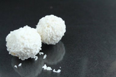 Bir iki üç hindistan cevizi serpiştirilmiş beyaz şekerler. Raffaello gibi parlak siyah bir arka planda yansıması olan bir kaç beyaz şeker. Metin için bir kopya alanı var.