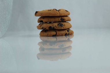 Üç dört ya da beş tane çikolatalı çikolata, fotokopi çekilişinin yansıması olan beyaz ışık arka planında üst üste istiflenmiştir.