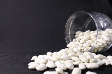 uzayın bir kopyasının siyah arka planına cam bir kavanozdan fasulye döküldü..