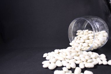 uzayın bir kopyasının siyah arka planına cam bir kavanozdan fasulye döküldü..