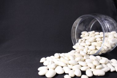 uzayın bir kopyasının siyah arka planına cam bir kavanozdan fasulye döküldü..