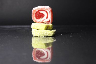 Üç pastil marmelatlı kırmızı ve limonlu kaydırak siyah glasant aynalı arka planda, içinde uzay kopyası olan boş bir alan var..