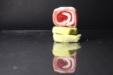 Üç pastil marmelatlı kırmızı ve limonlu kaydırak siyah glasant aynalı arka planda, içinde uzay kopyası olan boş bir alan var..