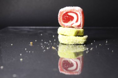 Üç pastil marmelatlı kırmızı ve limonlu kaydırak siyah glasant aynalı arka planda, içinde uzay kopyası olan boş bir alan var..