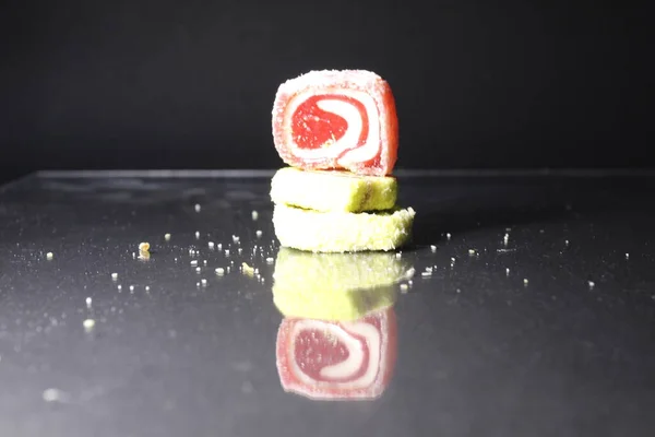 Üç pastil marmelatlı kırmızı ve limonlu kaydırak siyah glasant aynalı arka planda, içinde uzay kopyası olan boş bir alan var..