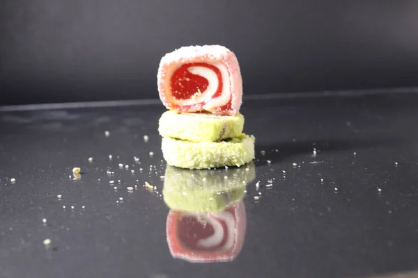 Üç pastil marmelatlı kırmızı ve limonlu kaydırak siyah glasant aynalı arka planda, içinde uzay kopyası olan boş bir alan var..