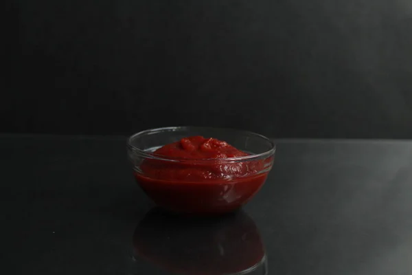 黒の背景にガラスのソースボウルに赤トマトソースペーストテキストのためのコピースペース — ストック写真