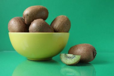 Sarı kase içinde kivi meyvesi ve yanında da kivi dilimi..