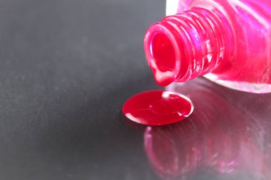 Güzellik arka planı pembe kırmızı tırnak cilası şişeden damlıyor siyah gri arka planda metin kopyasına yer var..