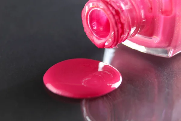 Güzellik arka planı pembe kırmızı tırnak cilası şişeden damlıyor siyah gri arka planda metin kopyasına yer var..