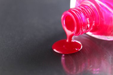 Güzellik arka planı pembe kırmızı tırnak cilası şişeden damlıyor siyah gri arka planda metin kopyasına yer var..
