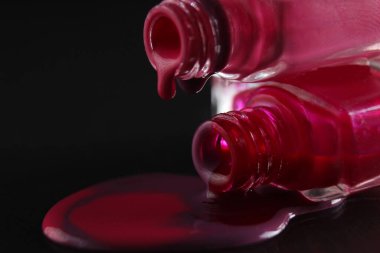 Tırnak cilasının akan damlaları. Kırmızı bordo kırmızı, siyah bir arka planda makro plan..