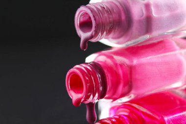 Kırmızı sakallı pembe tırnak cilası damlaları şişe şişesinden akmakta. Siyah, karanlık bir zemin üzerinde..