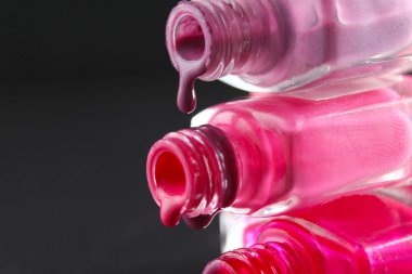 Kırmızı sakallı pembe tırnak cilası damlaları şişe şişesinden akmakta. Siyah, karanlık bir zemin üzerinde..