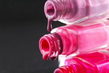 Kırmızı sakallı pembe tırnak cilası damlaları şişe şişesinden akmakta. Siyah, karanlık bir zemin üzerinde..